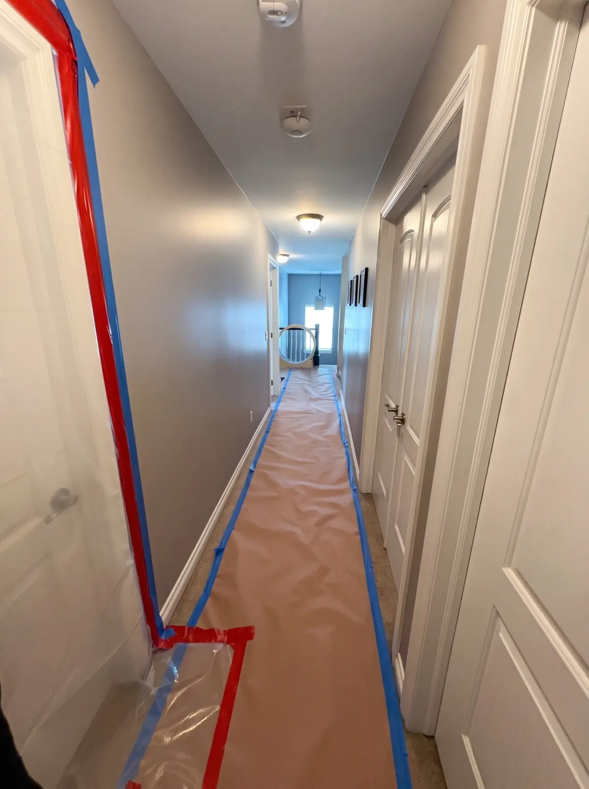 Hallway with floor protection paper and plastic containment taped along the wall before a water damage job