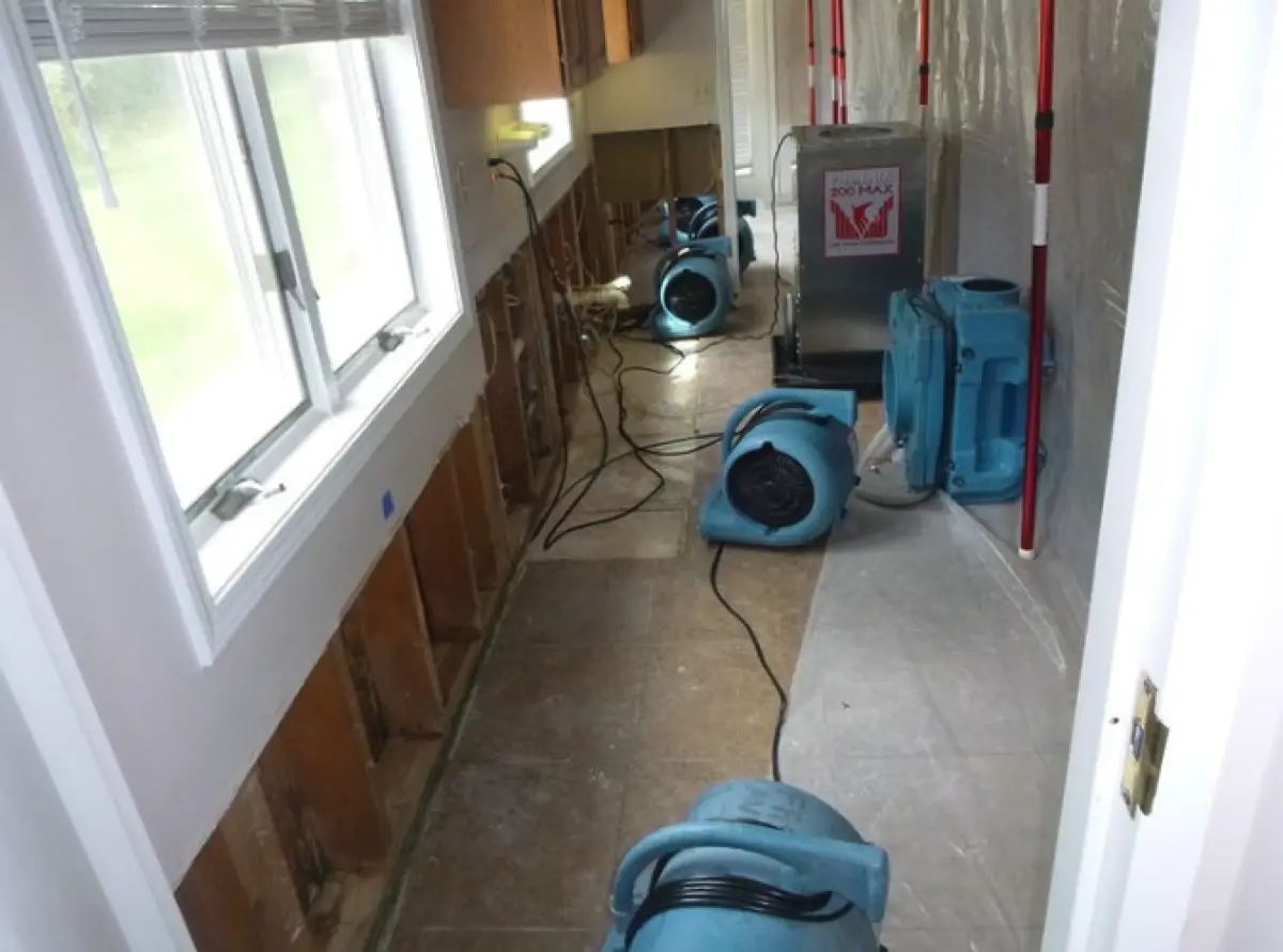 Kitchen with flood cuts along the lower cabinets and air movers running on the floor