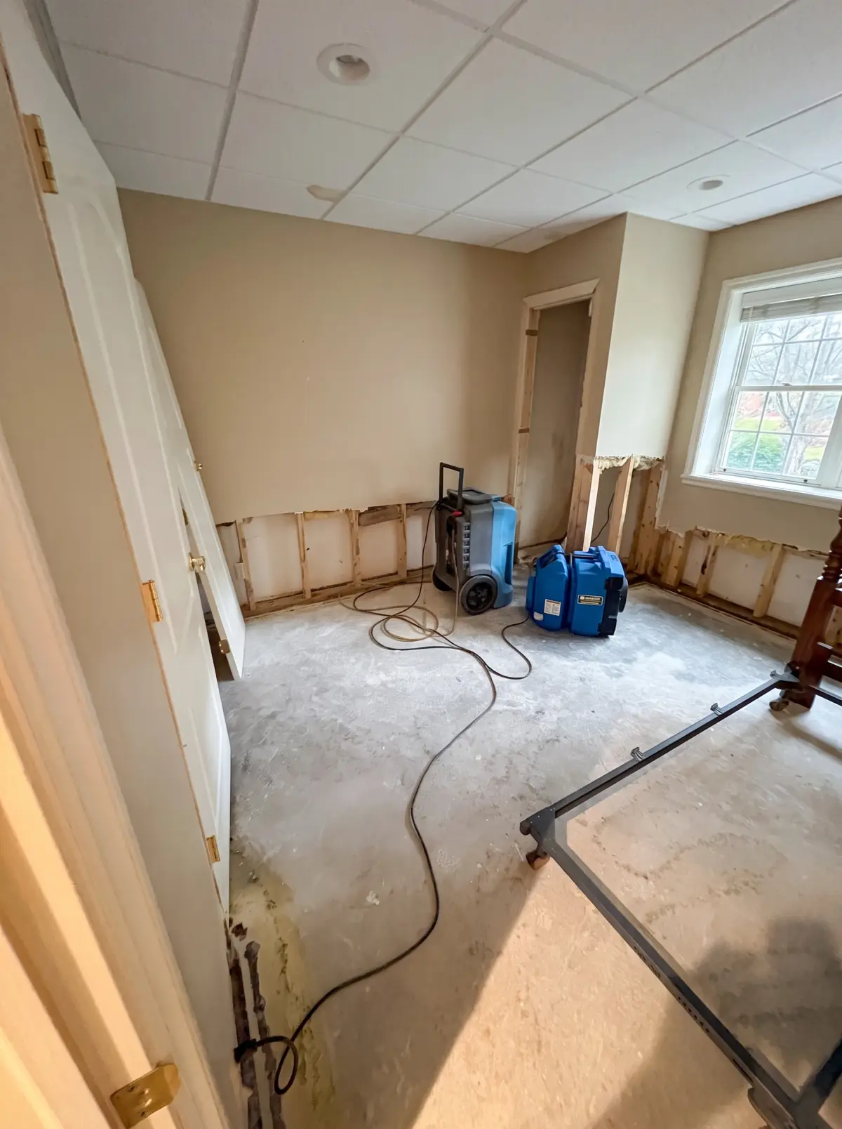 Basement room with drywall cut along the bottom and air movers drying the walls