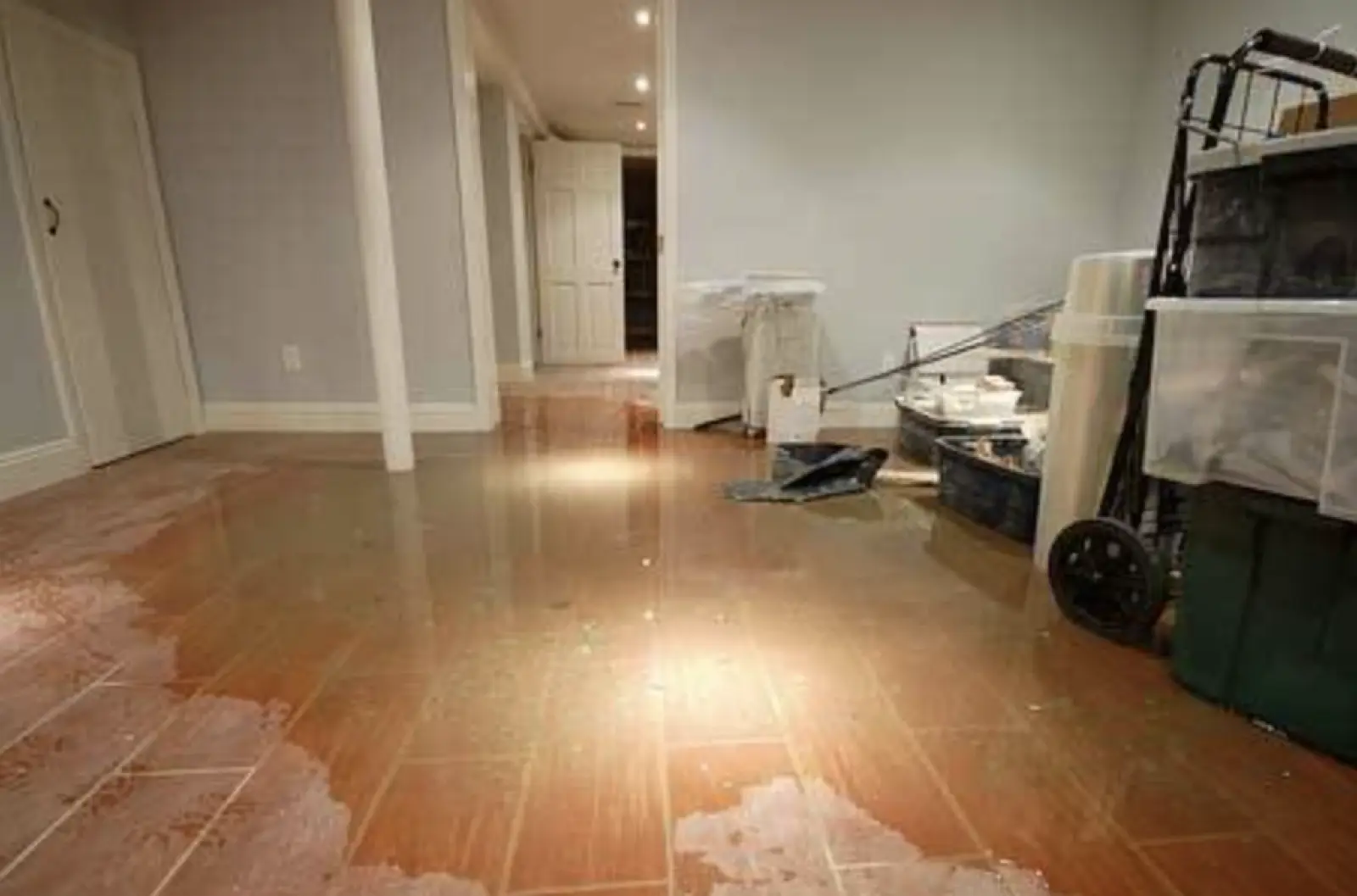 Finished basement with standing water covering the floor around boxes and furniture