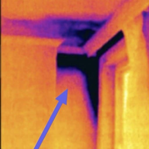 The same ceiling corner in thermal. A dark cold mass runs down the corner and along the ceiling: moisture that does not show in the photo.