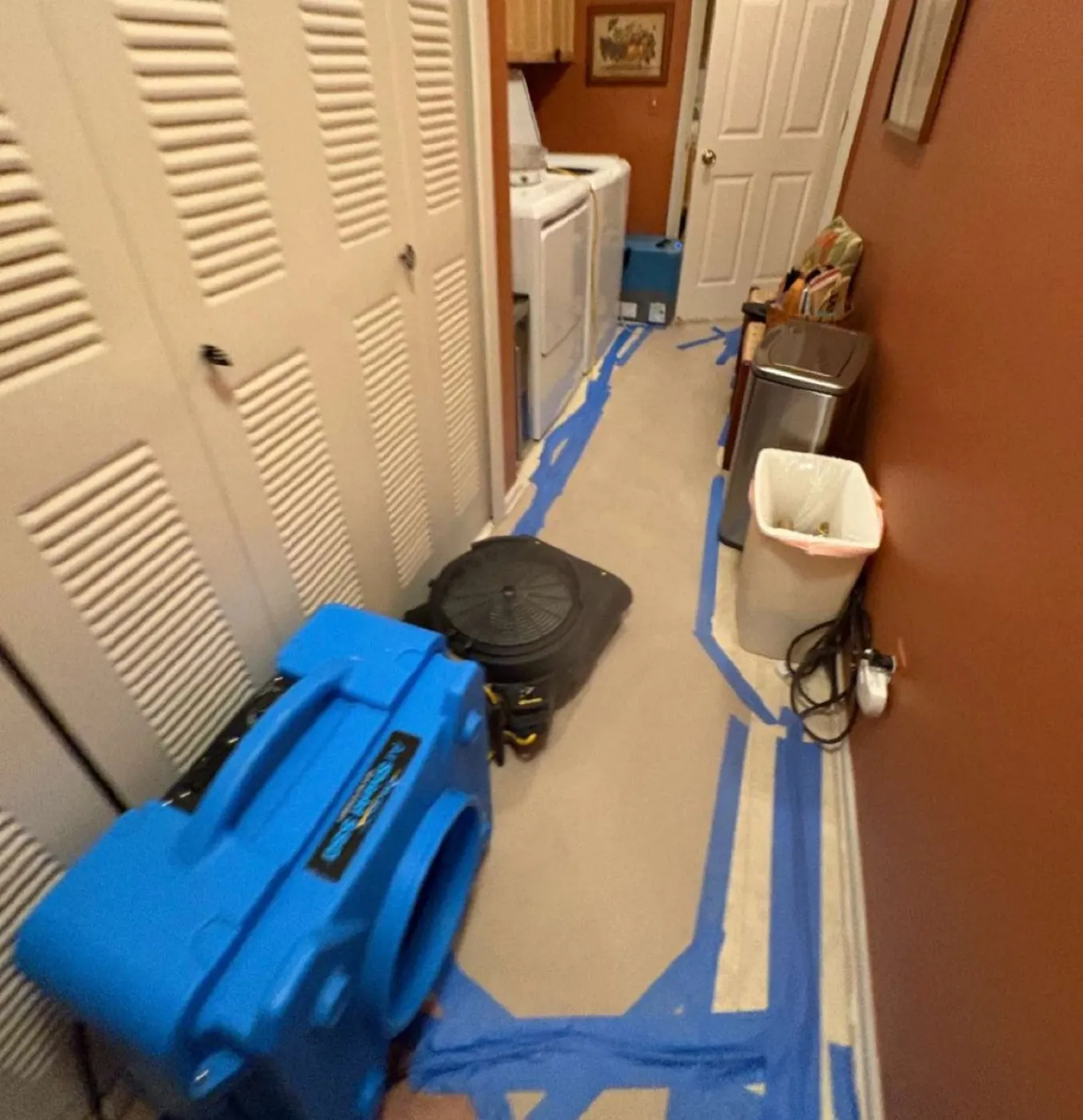 Air movers running along a hallway floor during a structural drying job