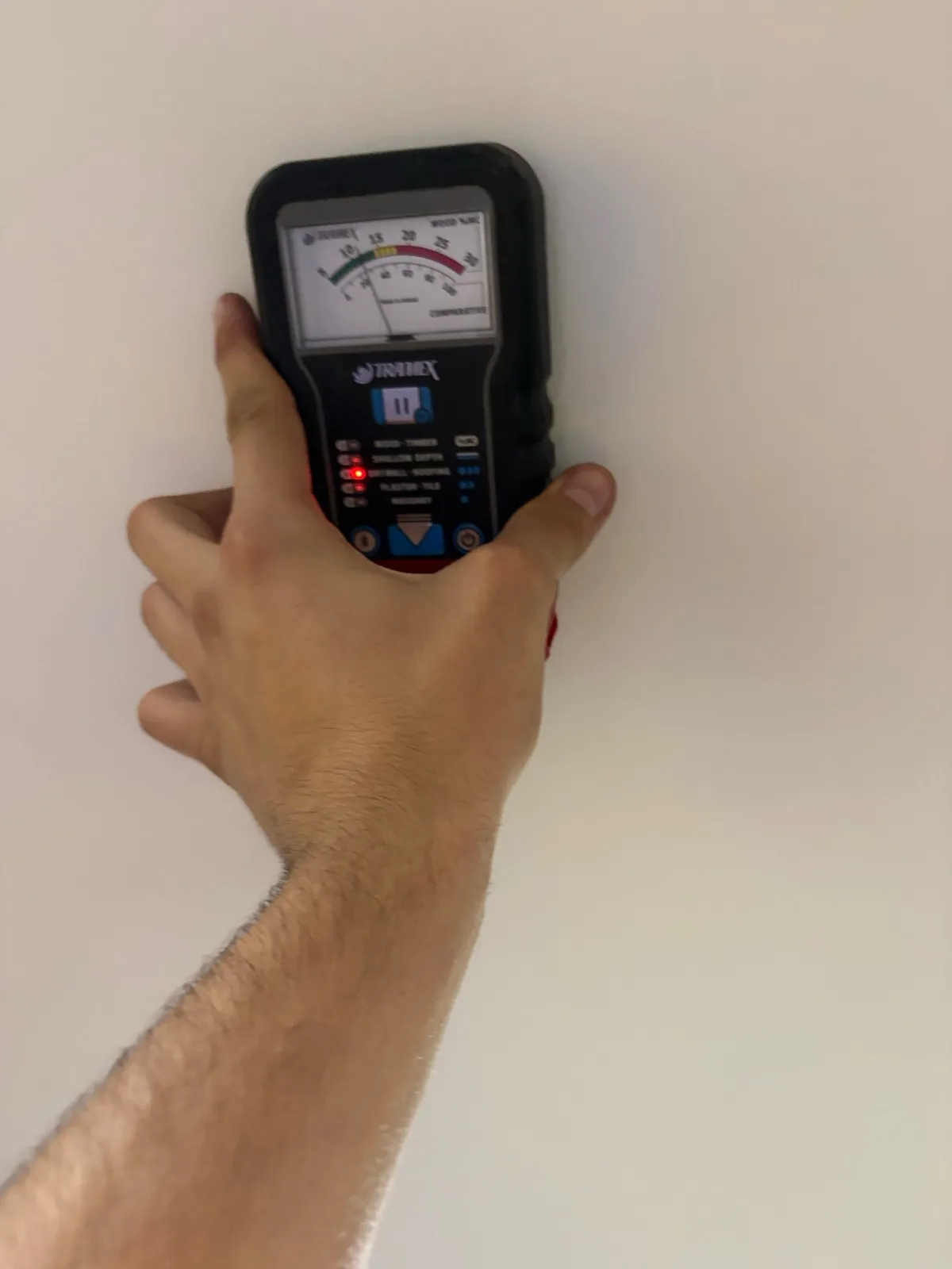 Hand holding a moisture meter against a ceiling to take a reading during a Prime Restoration inspection